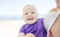 Cheerful baby girl in mother`s arms on beach Royalty Free Stock Photo