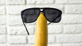 Cheerful banana in summer sunglasses on a background of a white brick wall,close-up