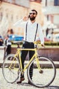 Cheerful beard man with beard talking on the mobile phone and smiling while standing near his bicycle. Royalty Free Stock Photo