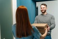 Cheerful bearded courier male delivering boxes with hot pizza to unrecognizable female customer on doorway at home. Royalty Free Stock Photo
