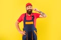 cheerful bearded deliveryman in work clothes on yellow background
