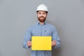 Cheerful bearded man builder holding copyspace blank