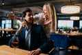 Cheerful bearded man in elegant suit talking on smartphone, turning around and looking at joyful pretty woman closed Royalty Free Stock Photo