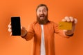 Cheerful bearded man showing cellphone screen and credit card, studio Royalty Free Stock Photo