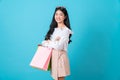 Cheerful beautiful Asian woman holding multi coloured shopping bags and crossed arms on light blue background. Royalty Free Stock Photo