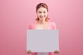 Cheerful beautiful asian young woman holding blank board on pink Royalty Free Stock Photo