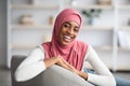 Cheerful beautiful black muslim woman in hijab posing in home interior