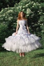 Cheerful beautiful bride jumping outdoors in white wedding dress and red sneakers. Funny concept