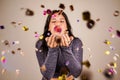 Cheerful beautiful brunette girl blowing confetti from her hands. Celebration of the holiday. Festive New Year& s Royalty Free Stock Photo