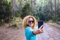 Cheerful beautiful caucasian woman adult take selfie picture in the forest enjoying trees and nature outdoor lesiure activity Royalty Free Stock Photo