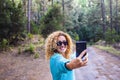 Cheerful beautiful caucasian woman adult take selfie picture in the forest enjoying trees and nature outdoor lesiure activity