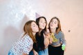 Lovely friendly girls celebrate birthday of their female friends and have fun standing on background of light wall in Royalty Free Stock Photo