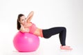 Cheerful beautiful fitness girl training abdominal muscles using fitball