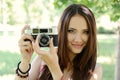 Cheerful beautiful girl talking pictures with vintage camera in summer park. Young woman photographer posing with her camera Royalty Free Stock Photo