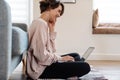 Cheerful beautiful girl working with laptop while sitting on floor Royalty Free Stock Photo