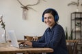 Cheerful beautiful Indian student woman wearing wireless headphones using laptop Royalty Free Stock Photo