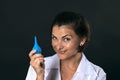 Cheerful beautiful nurse with an enema in her hand smiles mysteriously on a black background