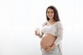 Cheerful beautiful pregnant woman holding glass of milk, white background Royalty Free Stock Photo