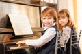 Cheerful beautiful small girls play piano together Royalty Free Stock Photo