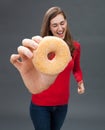 Cheerful beautiful woman holding a big appetizing donut as temptation Royalty Free Stock Photo