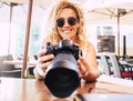 Cheerful beautiful woman with modern big professional reflex camera looking at the pictures in the back display smiling - people Royalty Free Stock Photo