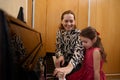 Cheerful beautiful woman pianist, musician teacher smiling while performing melody on piano, explaining music lesson to Royalty Free Stock Photo