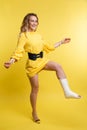 Cheerful beautiful woman in yellow dress having fun with plaster on her leg. Royalty Free Stock Photo