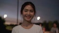 Cheerful beautiful young Asian woman feeling happy smiling to camera while traveling on street at downtown city in the night. Royalty Free Stock Photo