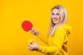 Cheerful beautiful young blonde woman in casual yellow sporty clothes play ping pong, holding a ball and racquet Royalty Free Stock Photo