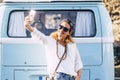 Cheerful beautiful young trendy adult woman take selfie picture smiling and having fun in outdoor leisure with blue vintage