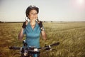 Cheerful beautiful young woman with a bike on a field fastens he