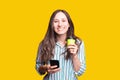 Cheerful beautiful young woman in casual drinking her morning tea or coffee and checking news on phone Royalty Free Stock Photo