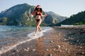 Cheerful bikini woman in Santa hat running carefree splashing water enjoying freedom Royalty Free Stock Photo