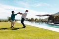 Cheerful biracial senior friends doing salsa dance on grassy land at poolside against sky in yard Royalty Free Stock Photo