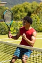 Cheerful biracial young man holding tennis racket pumping fist after winning game Royalty Free Stock Photo