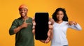 Cheerful Black Couple Holding And Pointing At Smartphone With Blank Screen Royalty Free Stock Photo