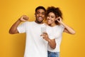 Cheerful black couple sharing headphones with smartphone Royalty Free Stock Photo