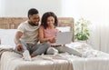 Cheerful black couple surfing the internet in bed Royalty Free Stock Photo