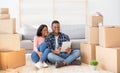 Cheerful black couple with touch pad to search for household goods for their new home online, using tablet on moving day Royalty Free Stock Photo