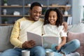 Cheerful black family father and daughter reading book at home Royalty Free Stock Photo