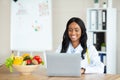 Cheerful black female dietitian using laptop pc, creating online weight loss program at modern clinic, free space