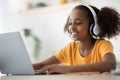 Cheerful black girl studying online, using laptop and headset Royalty Free Stock Photo