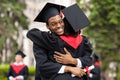 Cheerful black guy hugging his girlfriend while graduation ceremony