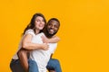 Cheerful black guy piggibacking his girlfriend, interracial couple having fun together Royalty Free Stock Photo