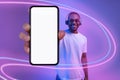 Cheerful black guy showing cell phone, using wireless headphones, mockup Royalty Free Stock Photo