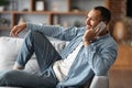 Cheerful Black Guy Talking On Cellphone And Relaxing On Sofa At Home Royalty Free Stock Photo