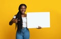 Cheerful Black Lady Holding And Pointing At White Blank Placard, Yellow Background Royalty Free Stock Photo