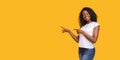 Cheerful black lady pointing at copy space on yellow