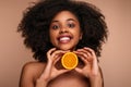 Cheerful black lady smiling and showing halved orange in studio Royalty Free Stock Photo