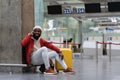 Smiling young African American hipster guy with suitcase calling on phone waiting flight in airport. Royalty Free Stock Photo